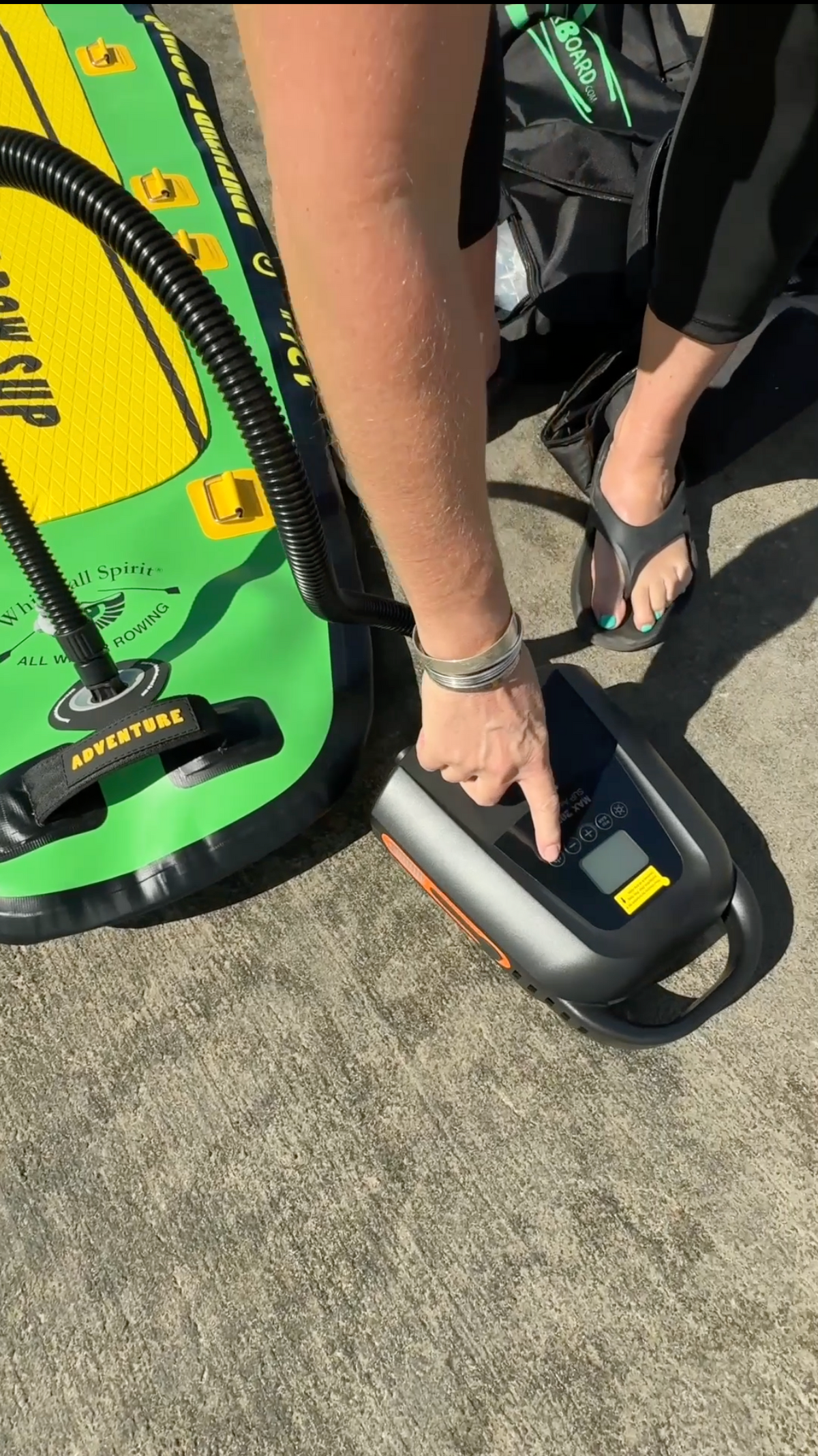 Electric pump connected to a green and yellow paddle board 