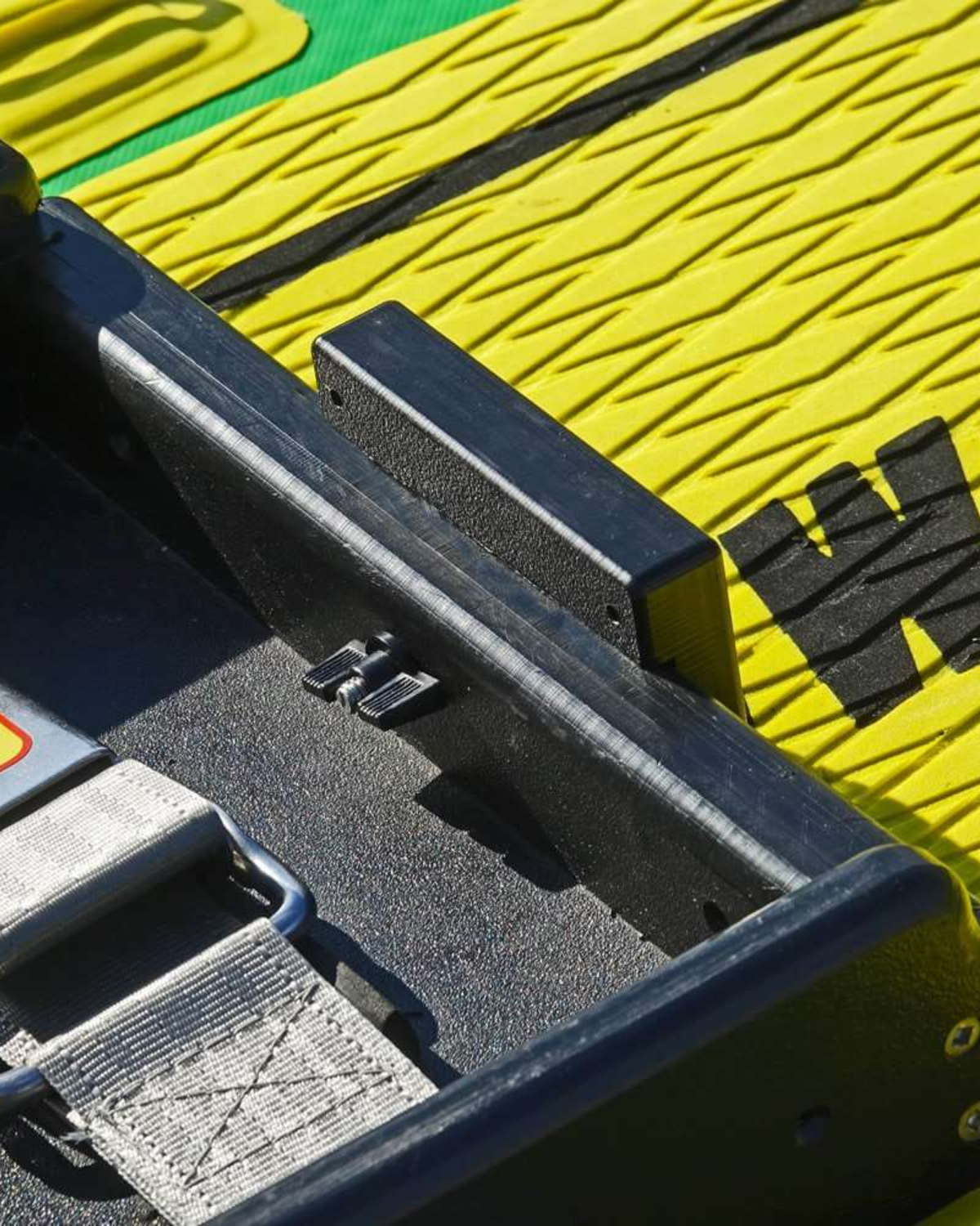 Close-up of mount attached to a molded black fixture on a bright yellow and green textured surface.