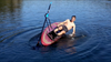 A man on a paddle board with a rowing attachment deliberately flipping it over and re-boarding it.  